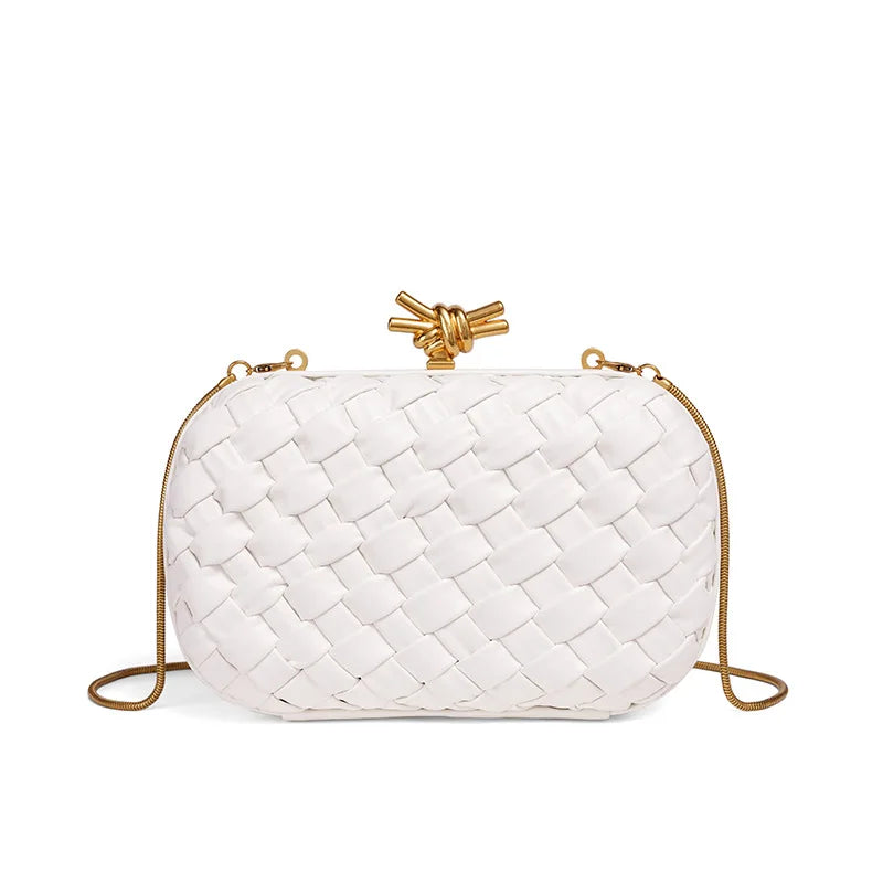 A white handwoven woven clutch bag with a gold chain strap is shown against a white background.