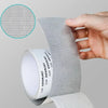 A hand is applying a self-adhesive fiberglass screen repair patch to a surface, showing the texture of the mesh material.