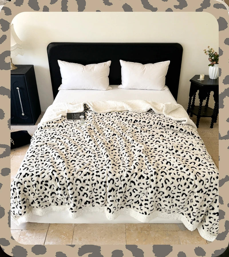 A leopard print plush jacquard throw blanket is displayed on a bed with white pillows and dark bedding.