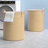 A striped yellow and white laundry basket with handles and a white towel resting inside, next to a washing machine.