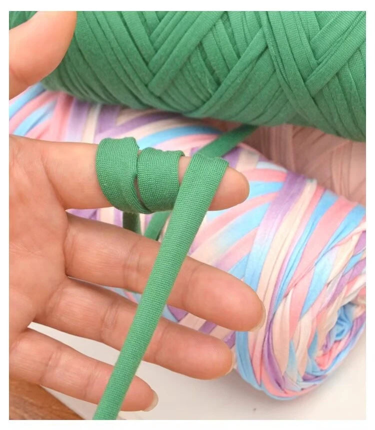 A hand is shown manipulating thick green polyester blend yarn for knitting and crochet.