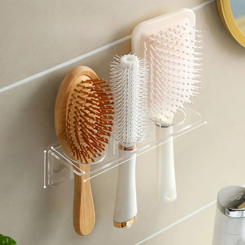 Wall-mounted acrylic organizer holding wooden and white hairbrushes on a light-colored wall.