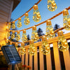 String lights with glowing bulbs hang over a wooden fence, powered by a solar panel.