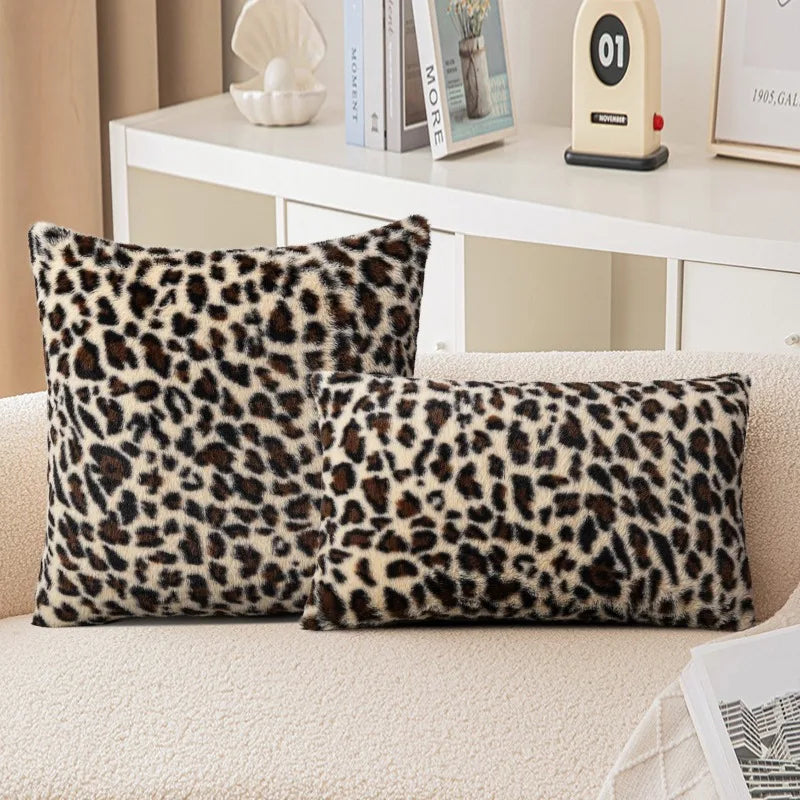 Two plush velvet leopard print pillows resting on a light-colored sofa.