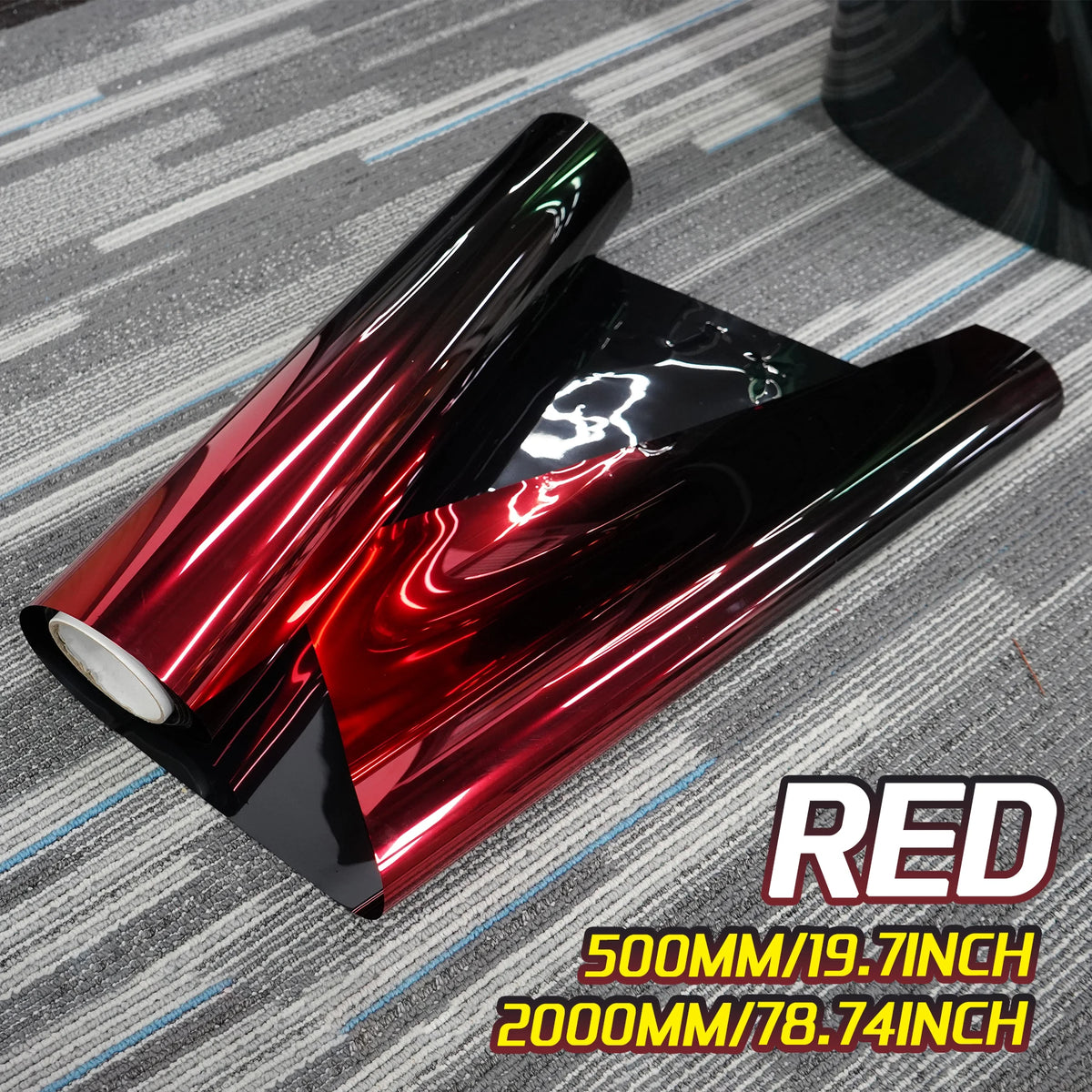 A roll of deep metallic red car window tint film displayed on a gray textured surface.