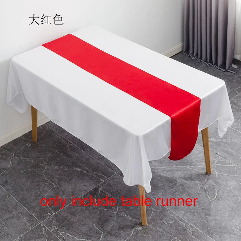 A white tablecloth with a red satin table runner is displayed on a table.