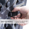 A hand is installing or removing black wheel cap covers on a car hub bolt.
