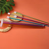 A set of 23 Tunisian crochet hooks in various colors with bamboo cables displayed on an orange background.