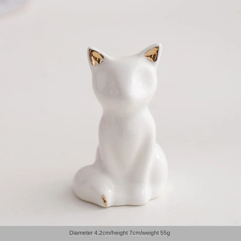 White ceramic elephant and rabbit jewelry holder with gold accents, sitting on a white surface.