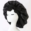 Black satin silk sleep bonnet tied in a large bow displayed on a white mannequin head.