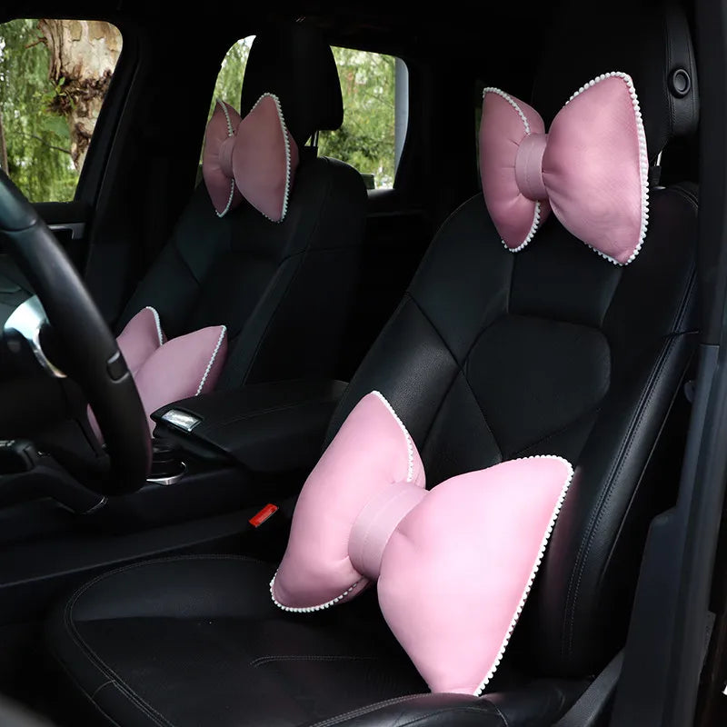 Pink silky bow car headrest pillow and waist cushion set shown in a black car interior.