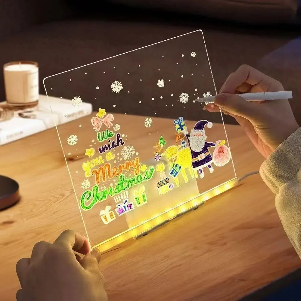A hand holds a glowing LED drawing board displaying a Christmas message and snowflakes.