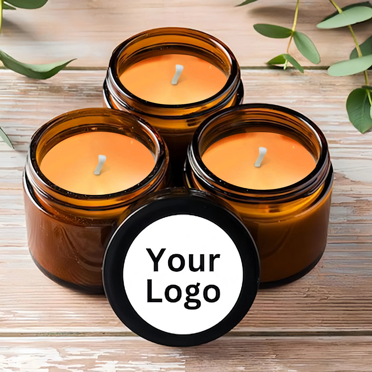 Three amber glass jars filled with orange scented soy candles and a black logo stamp on the front.