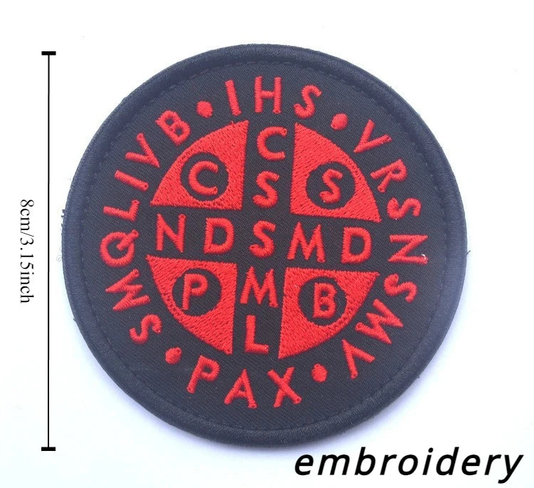 A black embroidered patch featuring the IHS monogram and the acronyms QLIVB, CNS, and others in red thread.
