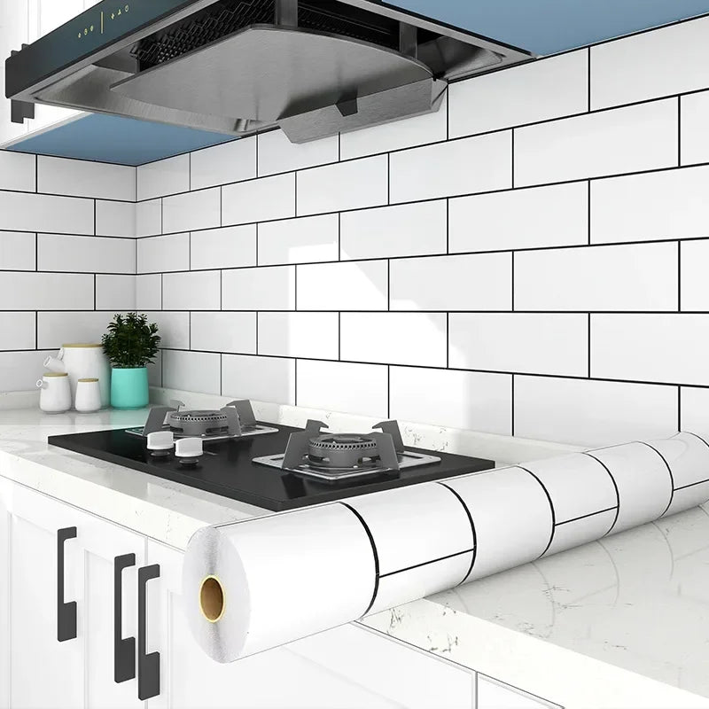 A white kitchen splashback tiled with subway tiles, featuring a stainless steel range hood above a countertop and a roll of w