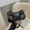 A black leopard print PU leather shoulder bag is held by a hand against a light background.