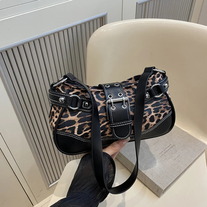 A black leopard print PU leather shoulder bag is held by a hand against a light background.
