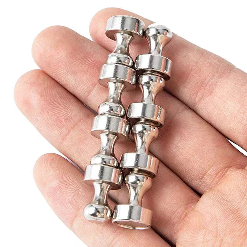 A hand holds a set of silver neodymium magnetic pushpins for various surfaces.
