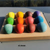 Holztablett mit zehn farbenen, kugelförmigen Blüten in Regenbogenanordnung für ein Musikspielzeug.