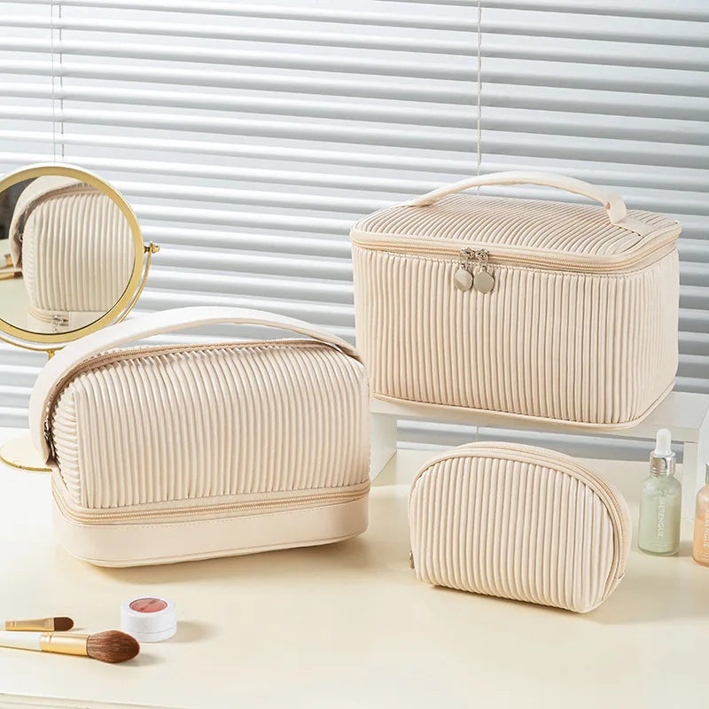 A set of three beige PU leather makeup bags, including a zippered case and a mirror, displayed on a light surface.