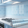 A kitchen display showing self-adhesive splashback stickers used as wallpaper on light blue tiles.