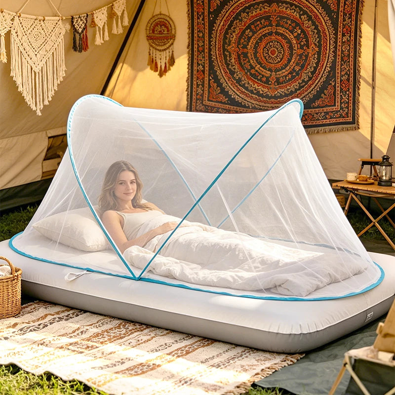 A white pop-up mosquito net with a zip closure is set up on the ground in an outdoor tent environment.