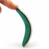 A hand is holding a green polishing pad with a silver edge, showing its texture and shape.