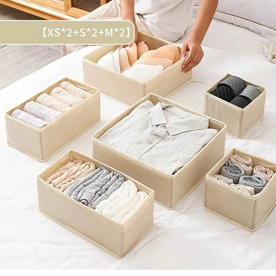 A collection of beige foldable drawer organizer boxes filled with various folded underwear, bras, and socks.