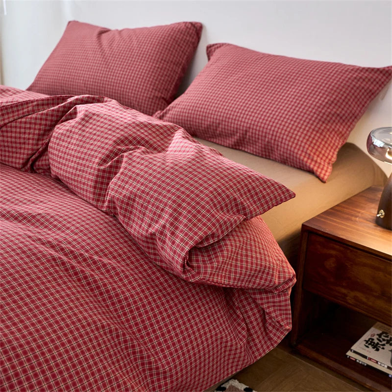 A close-up of a red and white plaid duvet cover with matching pillows on a bed.