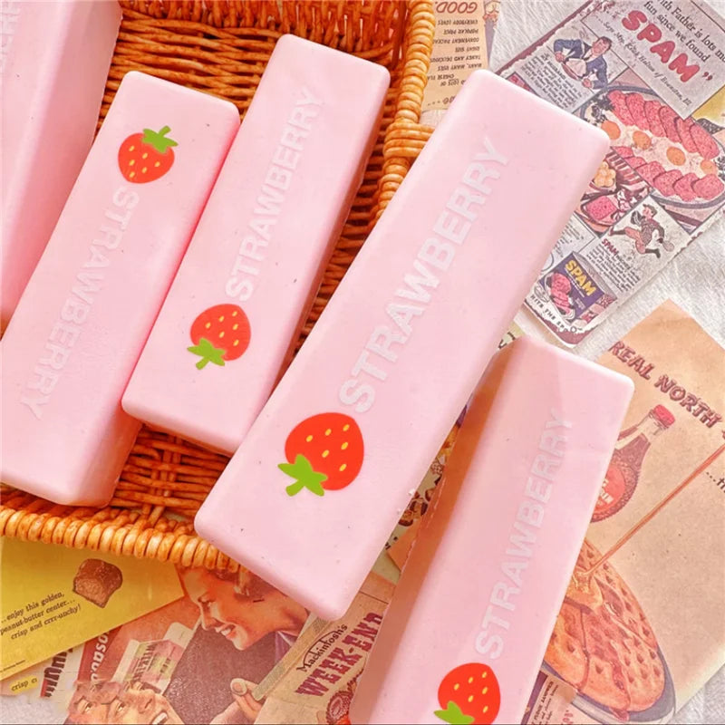 Pink strawberry squishy butter block fidget toy placed on a woven tray next to newspaper.
