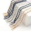 A collection of classic metal chain purse straps in black, silver, and gold tones laid out on a white surface.