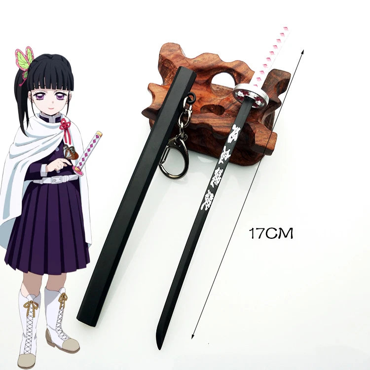 A miniature replica of a Demon Slayer katana sword with a black handle and pink hilt, displayed next to an anime-style female