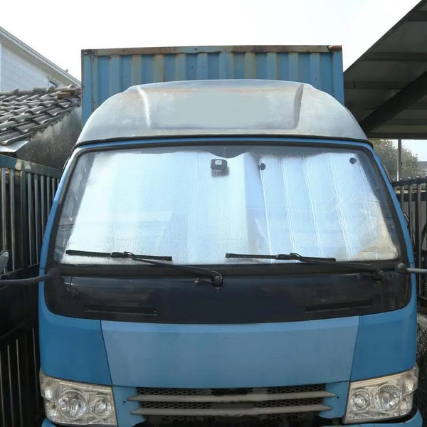 A blue heavy-duty truck windshield sun shade installed on a vehicle.