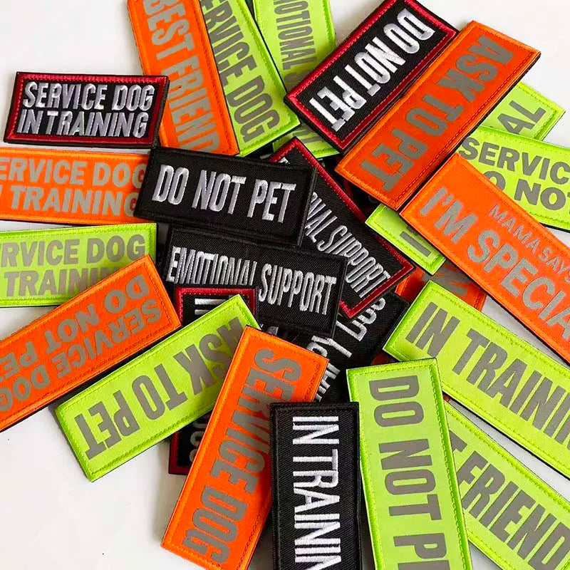 A collection of embroidered service dog training patches in various colors like orange, green, and black.
