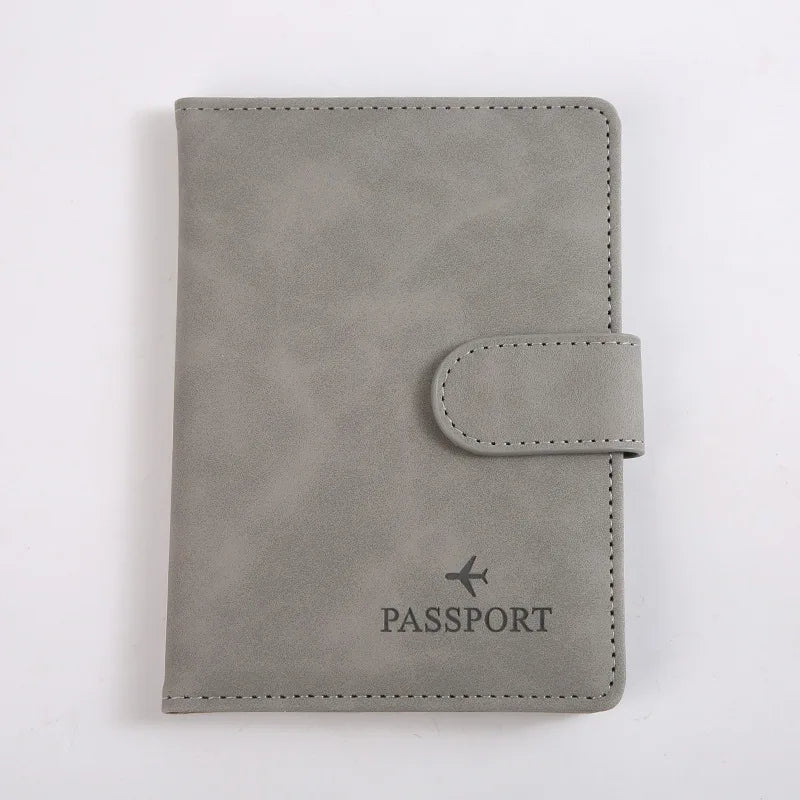 Porte-passeport en cuir gris avec rabat et petite languette en cuir.
