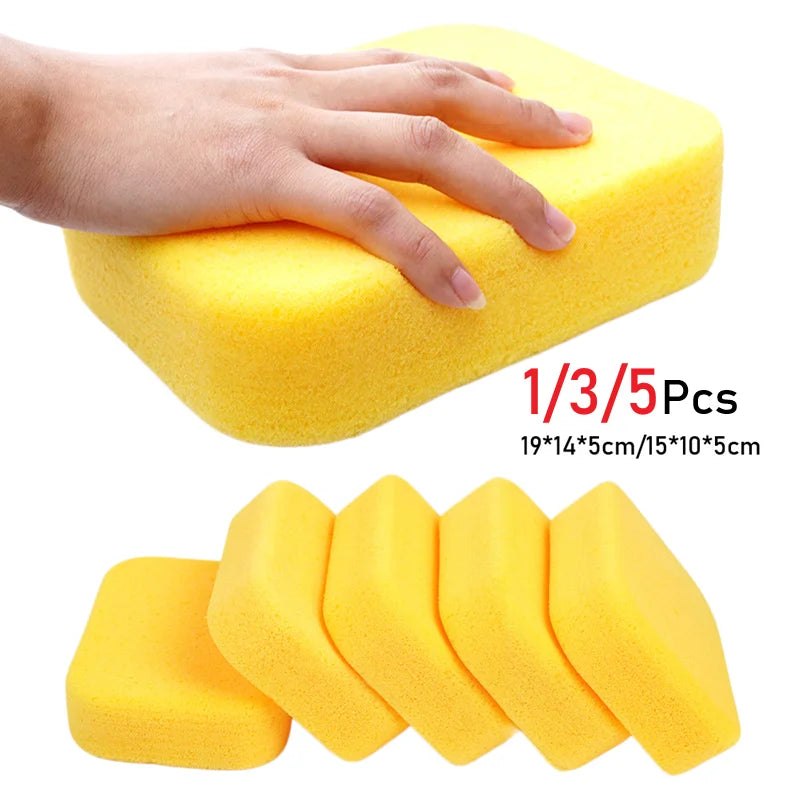 A hand is squeezing a yellow high-density car wash sponge set for auto detailing and waxing.