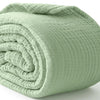 A tightly rolled, light sage green muslin cotton blanket or throw.
