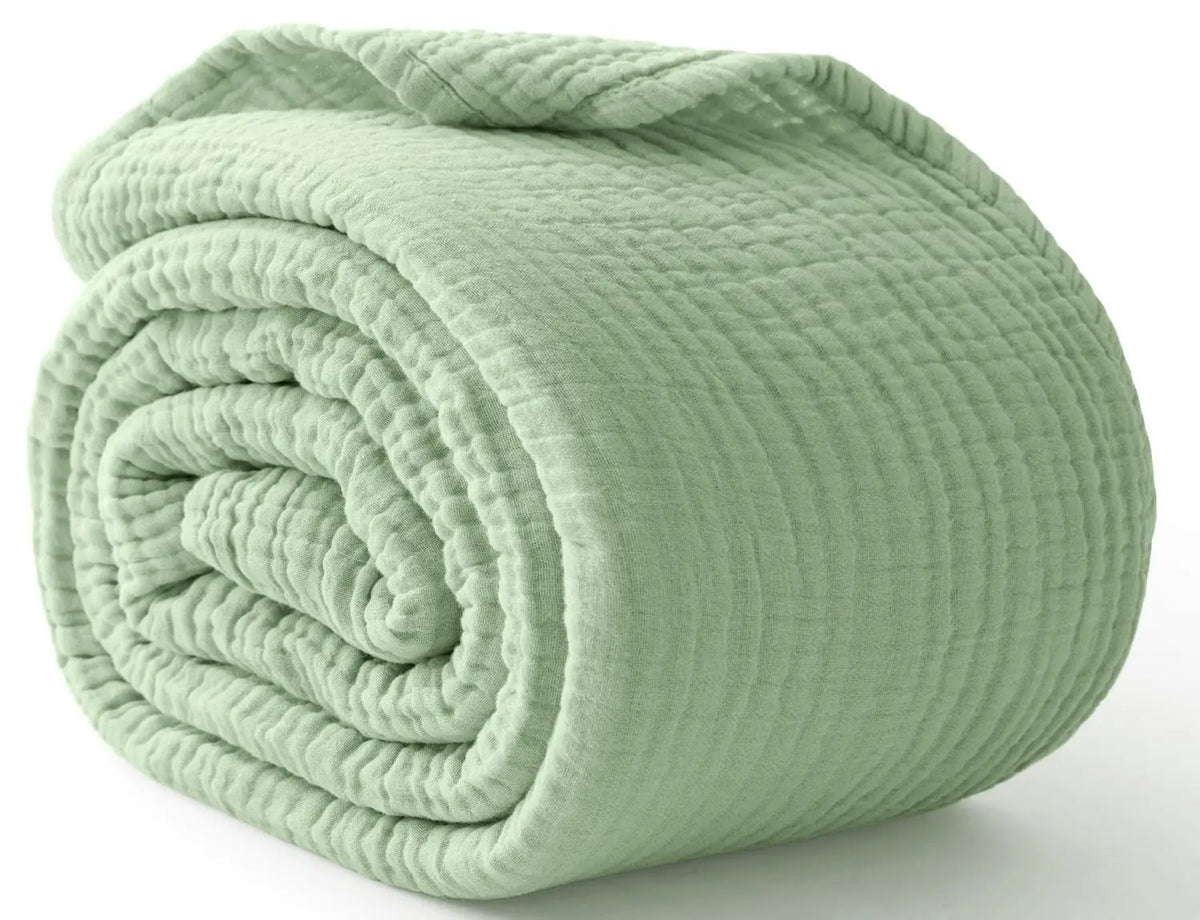 A tightly rolled, light sage green muslin cotton blanket or throw.