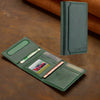 A dark green magnetic wallet phone case with card slots and a kickstand resting on a brown surface.