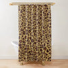 A beige leopard print shower curtain hanging from a gold rod.