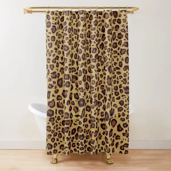 A beige leopard print shower curtain hanging from a gold rod.
