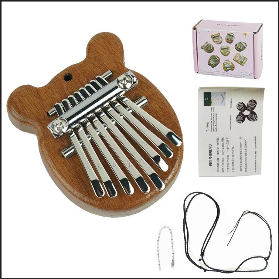 A wooden kalimba thumb piano with a metal tuning mechanism and attached wires, shown next to a box of tuning keys.