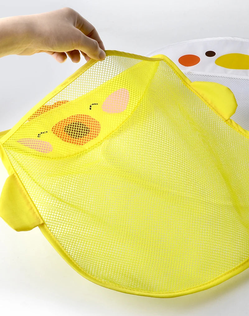 A hand is holding a bright yellow mesh bag shaped like a cartoon duck for bath toy storage.