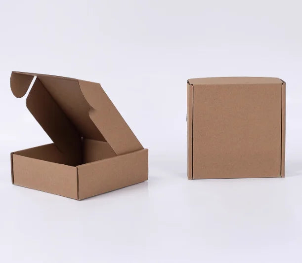 Eine braune Wellpappkarton ist geöffnet und eine geschlossene Box daneben zu sehen.