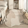 A light beige irregular area rug is placed on a wooden floor, partially illuminated by sunlight.