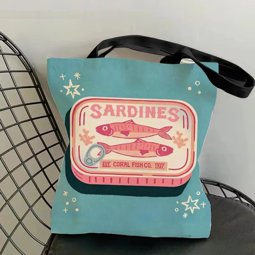 A light blue canvas tote bag featuring a graphic print of sardines and stars.