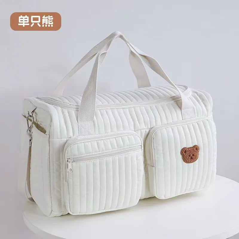 White embroidered cotton diaper bag featuring a bear design and quilted texture.