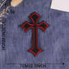 A black and red embroidered cross patch on a dark blue denim fabric.