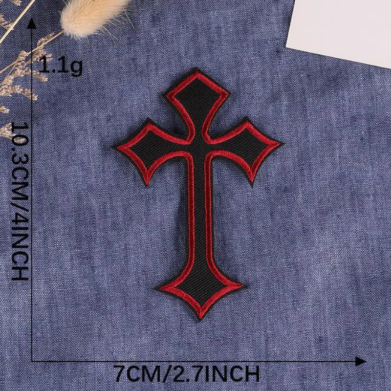 A black and red embroidered cross patch on a dark blue denim fabric.