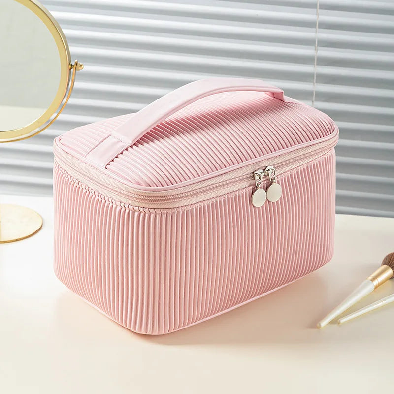 A pink ribbed PU leather makeup bag set with a lid and decorative hardware resting on a light surface.